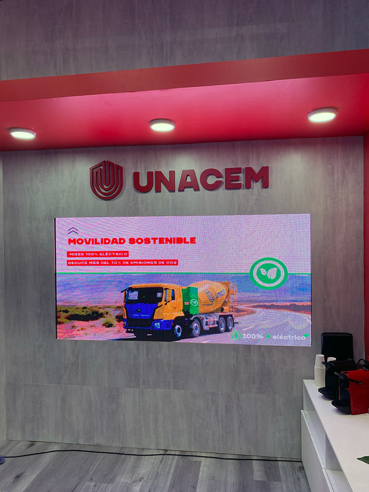 Interior del stand de UNACEM en Expo Edifica 2026 con pantalla LED y logo tridimensional